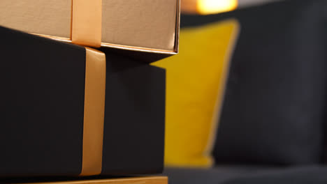 Close-Up-Of-Person-Putting-Gift-Wrapped-Presents-With-Bows-On-Table-In-Lounge-At-Home